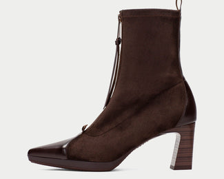 A dark brown ankle boot with a pointed toe, a chunky block heel, and a side zipper with a tassel detail, shown against a light gray background.