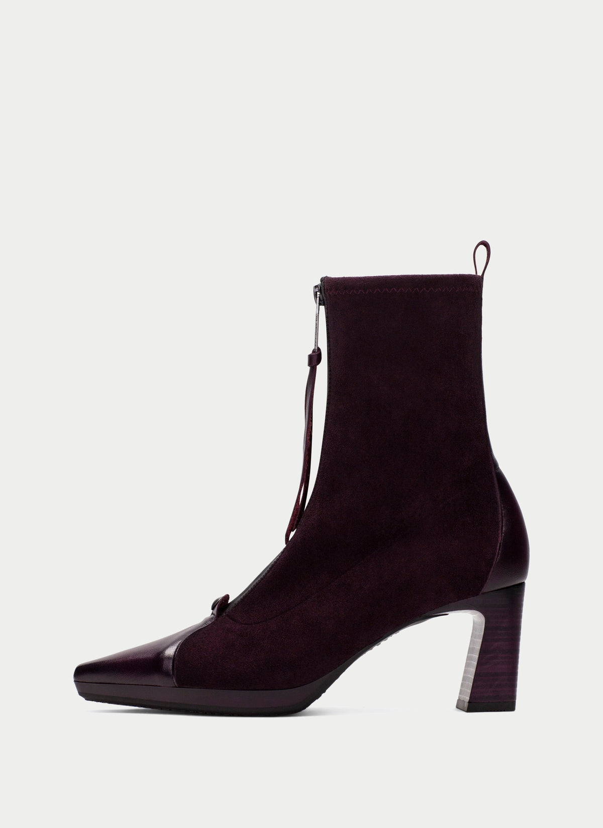 A dark plum purple suede ankle boot with a glossy patent leather toe cap and a block heel, shown from a side profile on a light gray background.