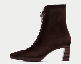 A dark brown suede lace-up ankle boot with a chunky block heel, shown in profile against a light gray background.