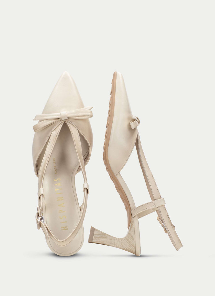 Beige high-heeled shoes with a bow on a light gray background