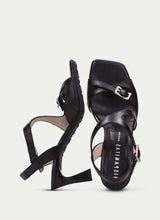 Load image into Gallery viewer, Black high-heeled sandals with 'Hispanitas' branding on a light gray background
