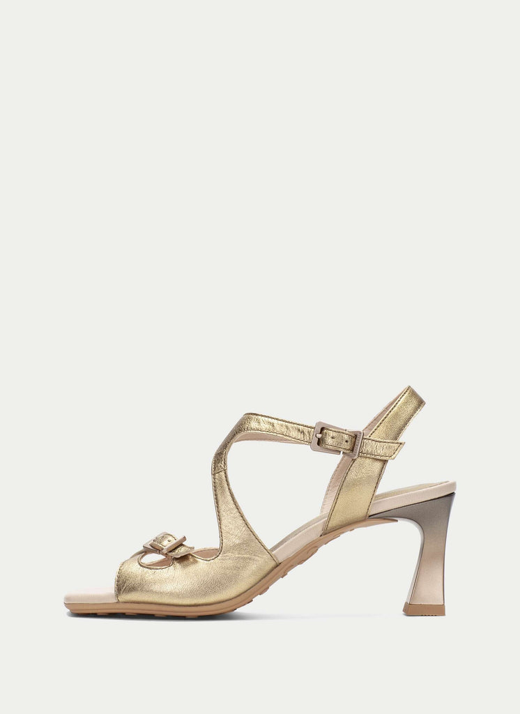 Gold high-heeled sandal on a light beige background