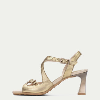 Gold high-heeled sandal on a light beige background