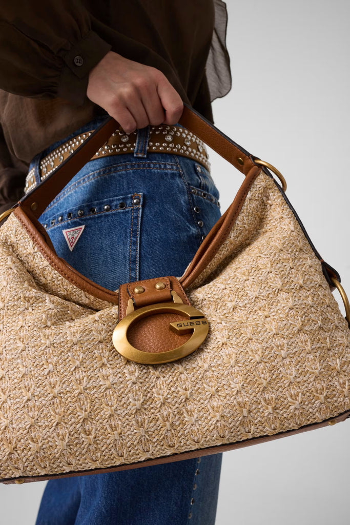 Person holding a beige handbag with a gold clasp against a neutral background