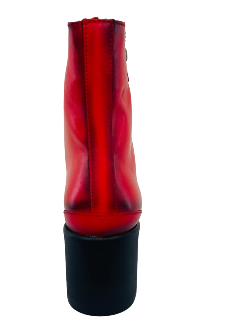 Red high-heeled shoe on a white surface with a neutral background