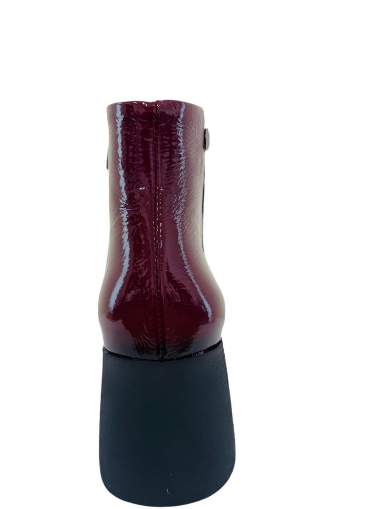 Shiny purple cylindrical object on a white surface with a white background