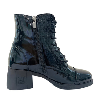 Black patent leather boot on a white surface with a light gray wall background