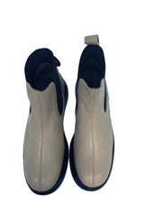 Load image into Gallery viewer, Pair of beige ankle boots with black soles on a white surface.
