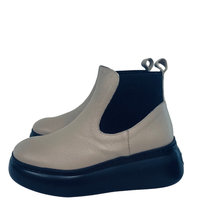 Pair of beige and black ankle boots on a white surface with a light gray background