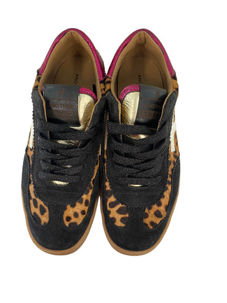 Sneaker with leopard print and black design on a white wall