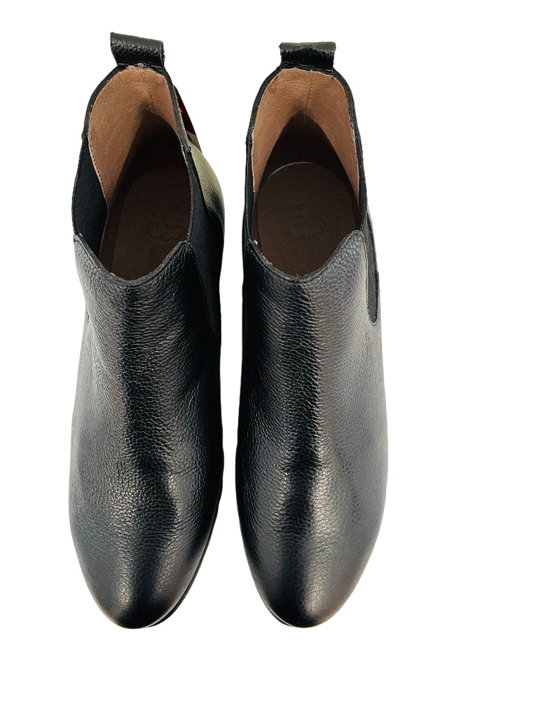 Pair of black leather shoes on a white surface with a wooden edge.