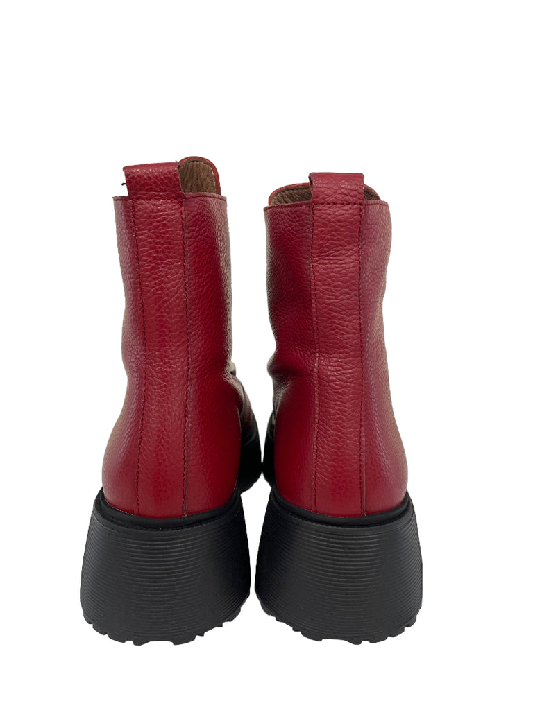 Pair of red boots with black soles on a white floor.