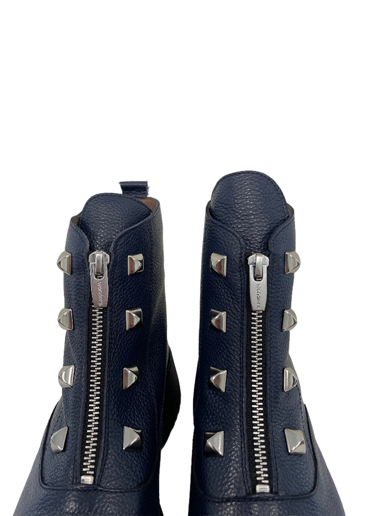 Two navy blue leather bags with silver zippers and studs on a white background
