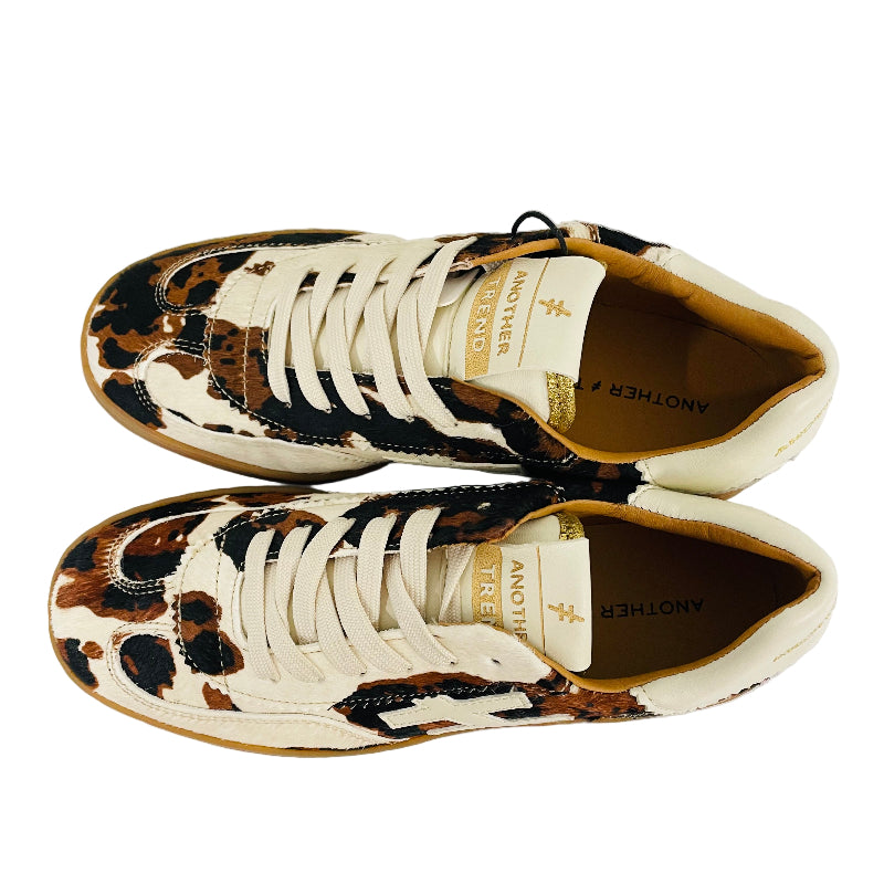 Pair of sneakers with leopard print soles on a white surface.