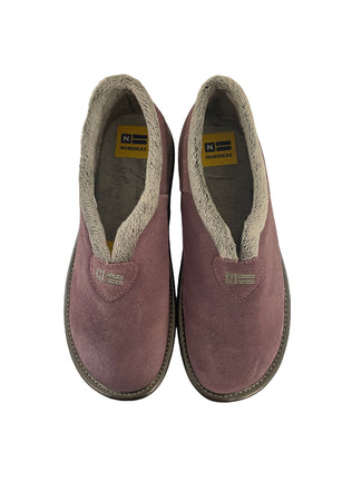 Purple slipper on a white radiator against a light gray wall