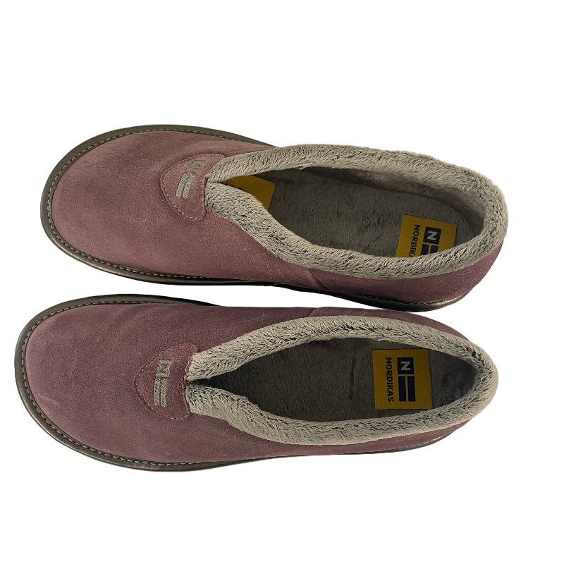 Pair of pink slippers with brand label on a white surface next to a radiator.