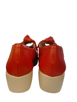 Red shoe with a white sole on a white surface