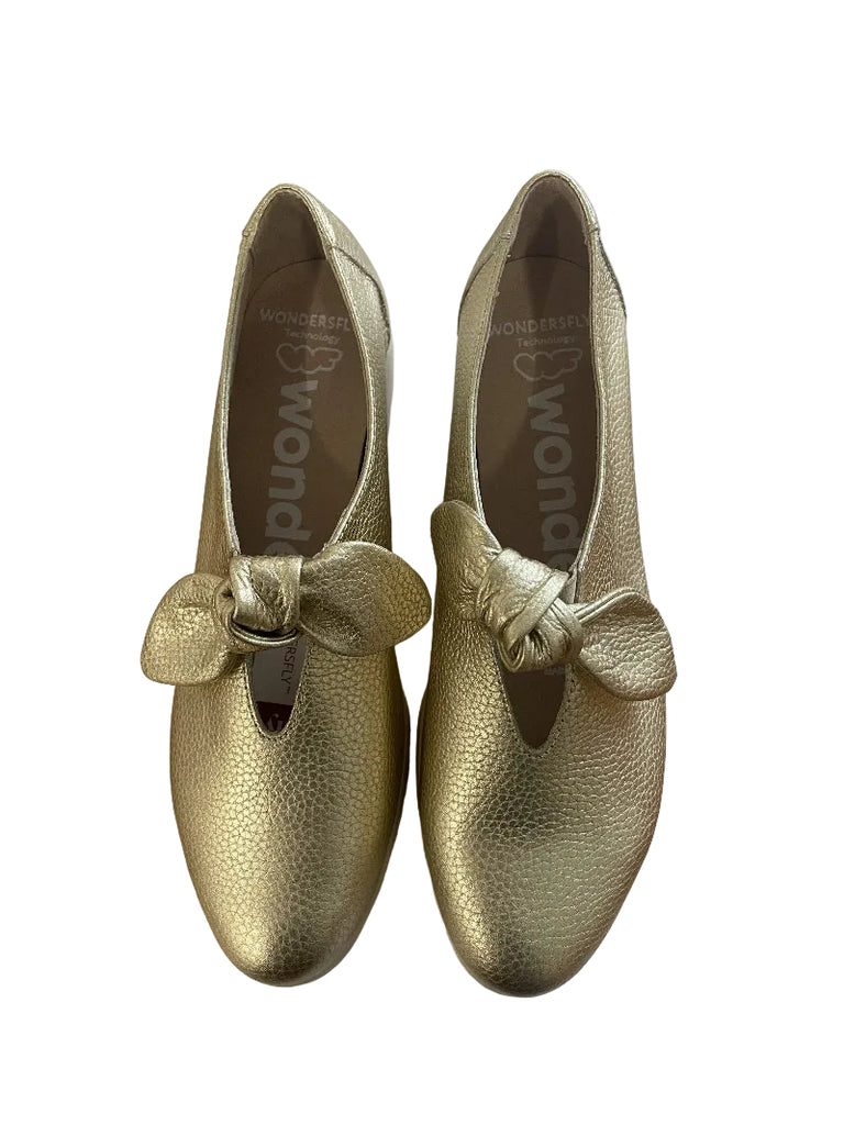 Gold shoes with bow details on a white surface