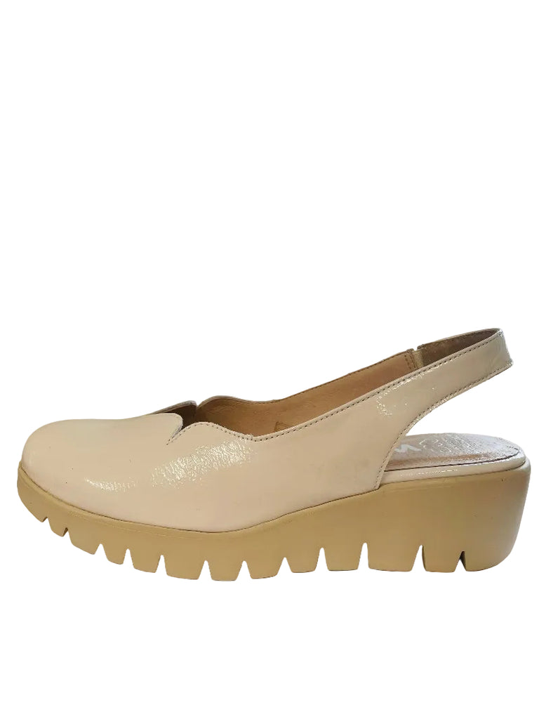 Beige platform sandal on a white surface with a window in the background