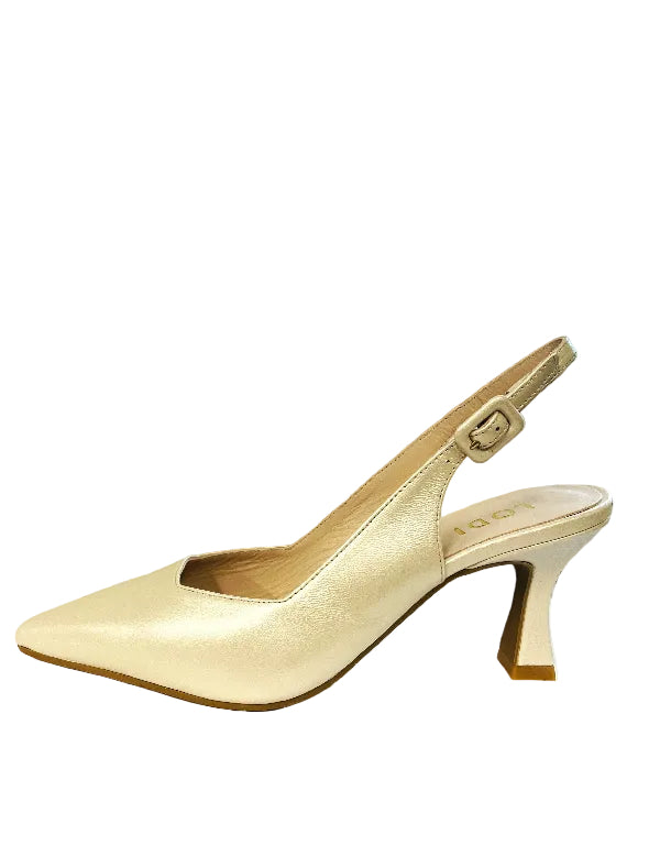 Beige high-heeled shoe on a white surface with a window in the background