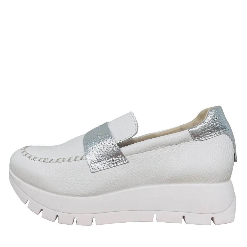 White shoe with silver accents on a wooden surface