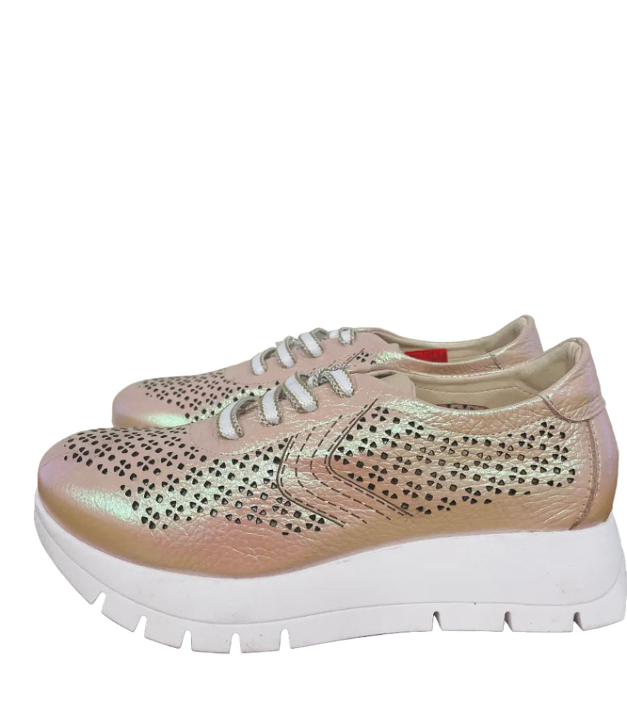 Pink sneakers with rhinestone details on a wooden floor.