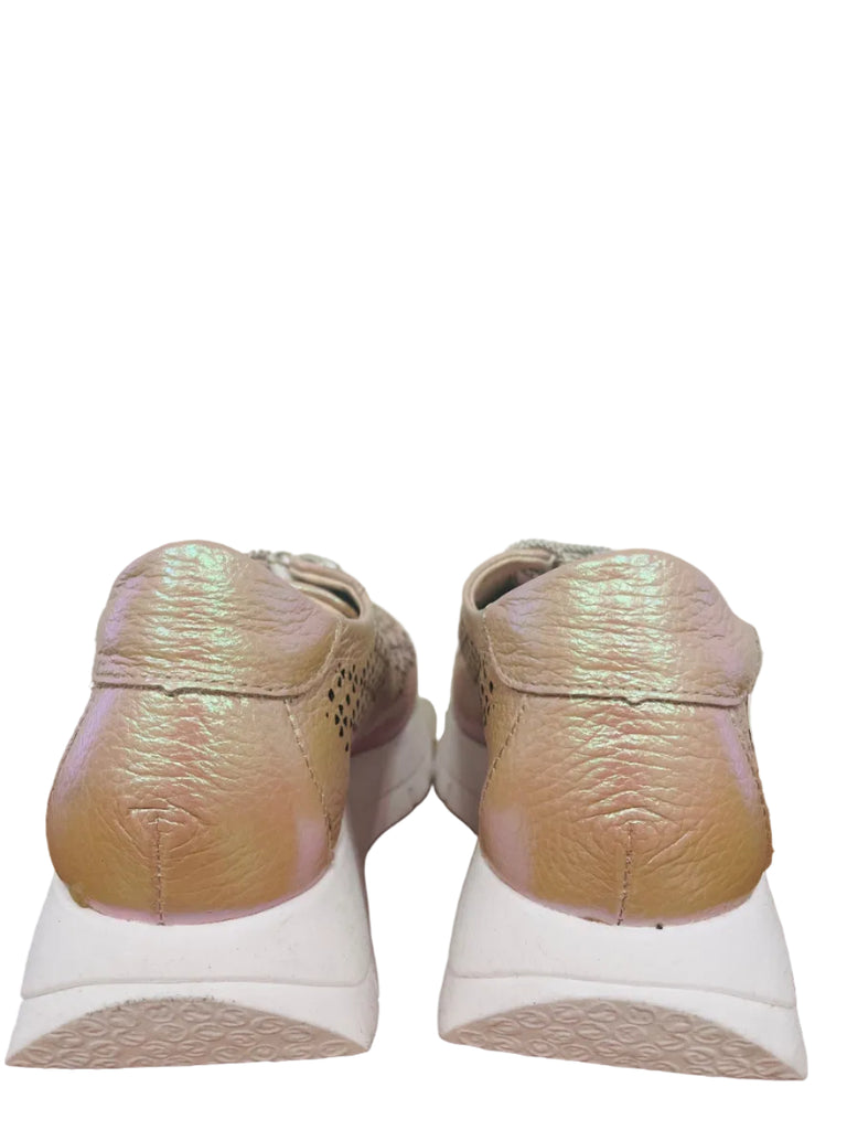 Pair of beige sneakers on a wooden floor with a white wall background