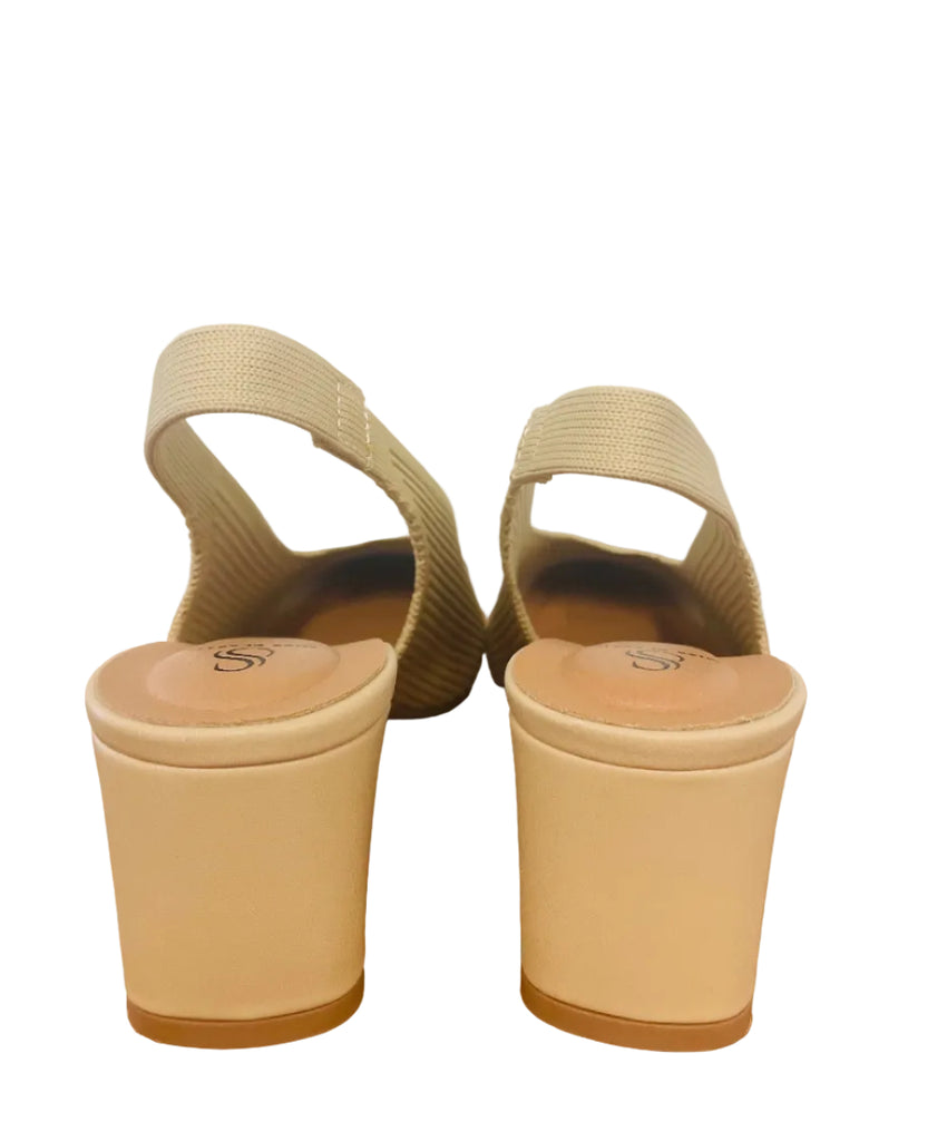 Pair of beige high-heeled sandals on a wooden surface with a blurred background