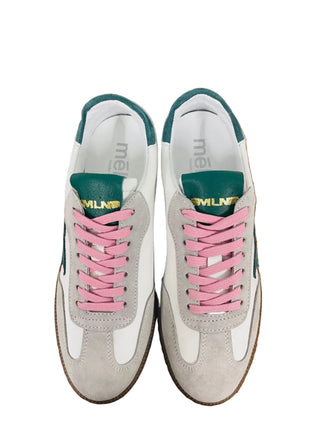 White sneaker with green star and pink laces on a wooden surface