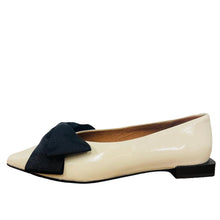 Load image into Gallery viewer, White flat shoe with a black bow on a wooden surface
