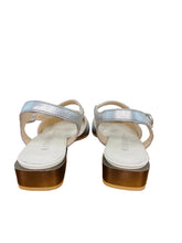 Load image into Gallery viewer, Pair of silver sandals with white soles on a wooden surface.
