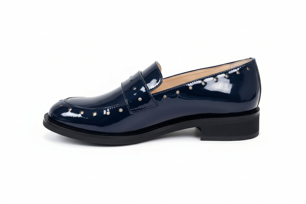 Navy loafer shoe with pearl embellishments on a wooden surface.