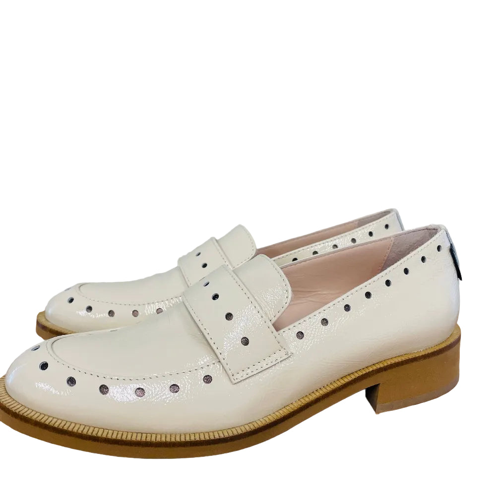 White loafers on a wooden surface with a light gray background