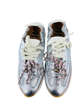 Load image into Gallery viewer, Pair of silver sneakers with pink laces on a wooden surface.
