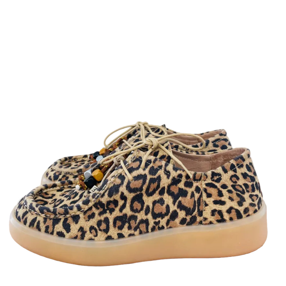 Leopard print sneakers on a wooden surface with a light gray background