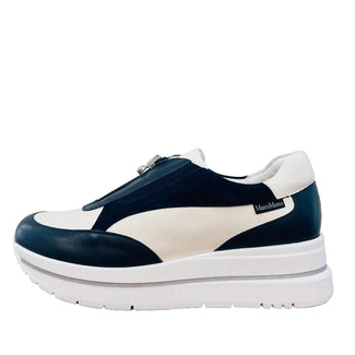 Navy and white sneaker on a wooden surface with a light gray background