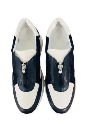 Navy and white sneaker on a wooden surface with a light gray background