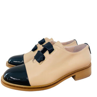 Beige and black shoe on a wooden surface with a white background