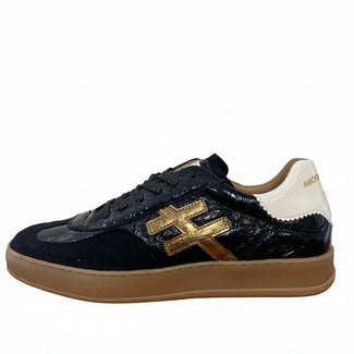 A single black leather sneaker with a prominent gold 'H' logo on the side, a white heel tab, and a beige gum sole, shown standing on a wooden floor against a plain wall.