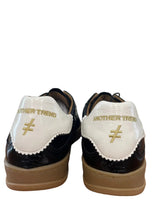 Load image into Gallery viewer, A pair of custom sneakers shown from the back, featuring white leather uppers with gold text reading 'ANOTHER TREND', a gold chevron symbol, and a black patent leather heel tab, set on a wooden floor.
