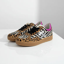 Load image into Gallery viewer, A pair of MOTHER &amp; DOLL low-top sneakers featuring a mixed animal print design with leopard print, zebra print, and black suede, accented with a metallic silver 'X' logo and a bright pink collar, on a white background.
