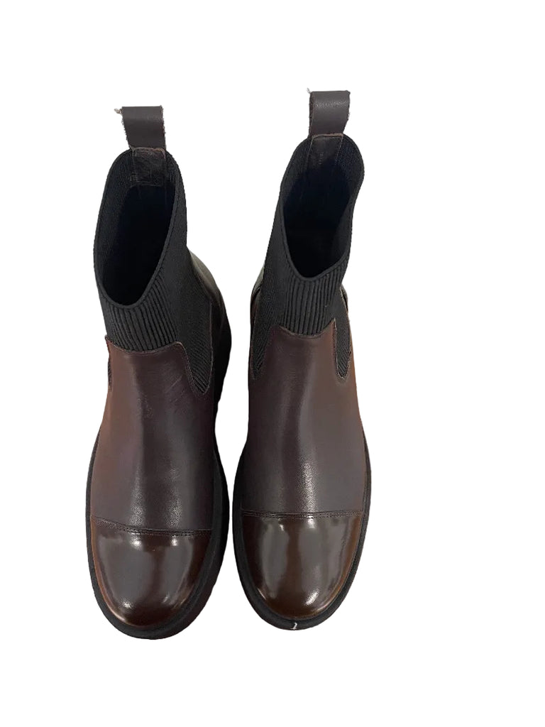 A pair of dark brown leather Chelsea boots with black elastic side panels and pull tabs, shown from a top-down view on a wooden surface.