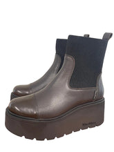 Load image into Gallery viewer, A pair of dark brown platform Chelsea boots with black ribbed elastic side panels, resting on a wooden surface against a plain light background.
