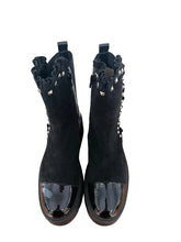Load image into Gallery viewer, A pair of black ankle boots with ruffled cutout details and shiny patent leather toe caps, displayed on a wooden surface against a white wall.
