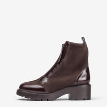 Load image into Gallery viewer, A dark brown ankle boot with a chunky lug sole and glossy patent leather panels, shown from a side profile on a light gray background.
