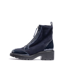 Load image into Gallery viewer, A dark navy blue ankle boot with a mix of matte suede and glossy patent leather panels, featuring a side zipper and a chunky black block heel, shown against a plain white background.
