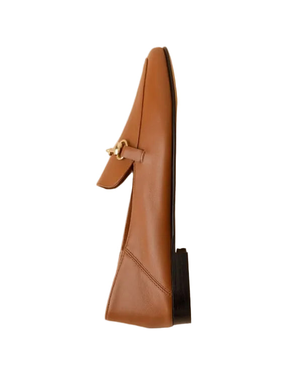 Brown leather loafer with a decorative buckle on a beige background