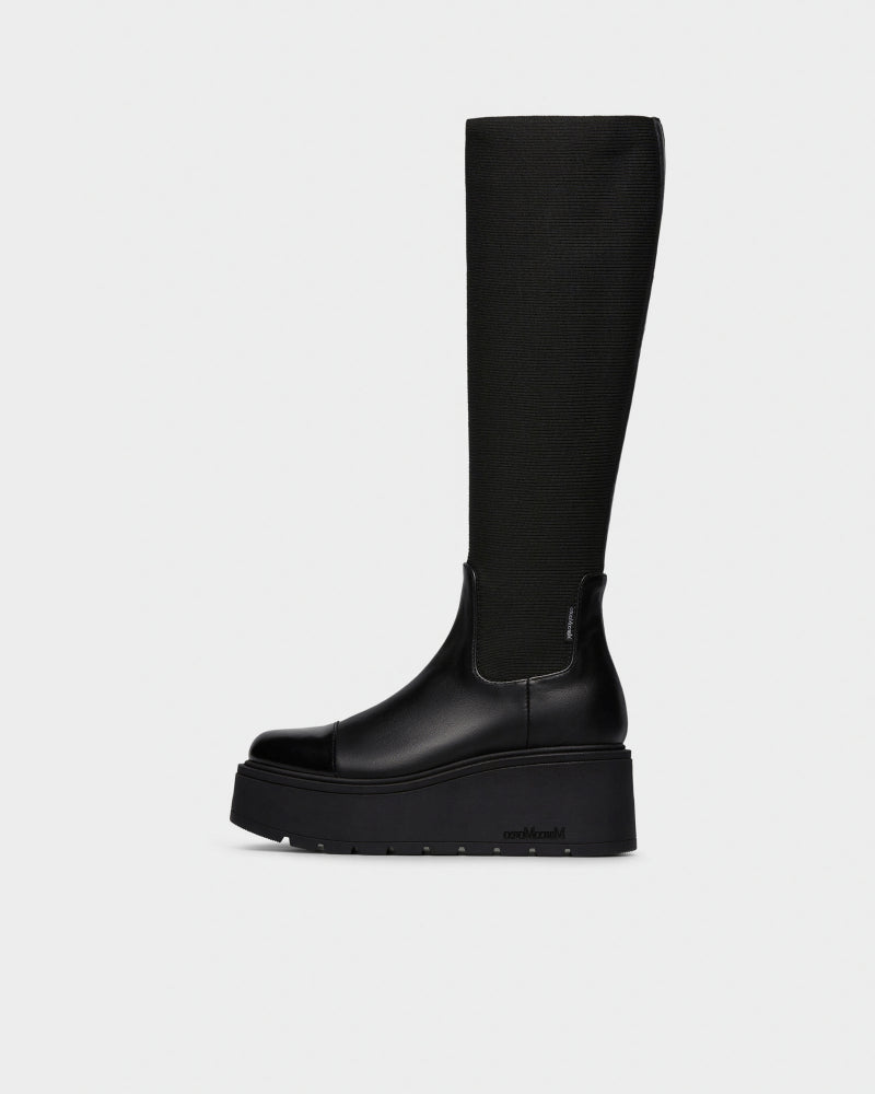 A single black knee-high boot with a chunky platform sole, shown in profile against a light gray background.