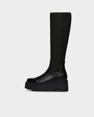 A single black knee-high boot with a chunky platform sole, shown in profile against a light gray background.