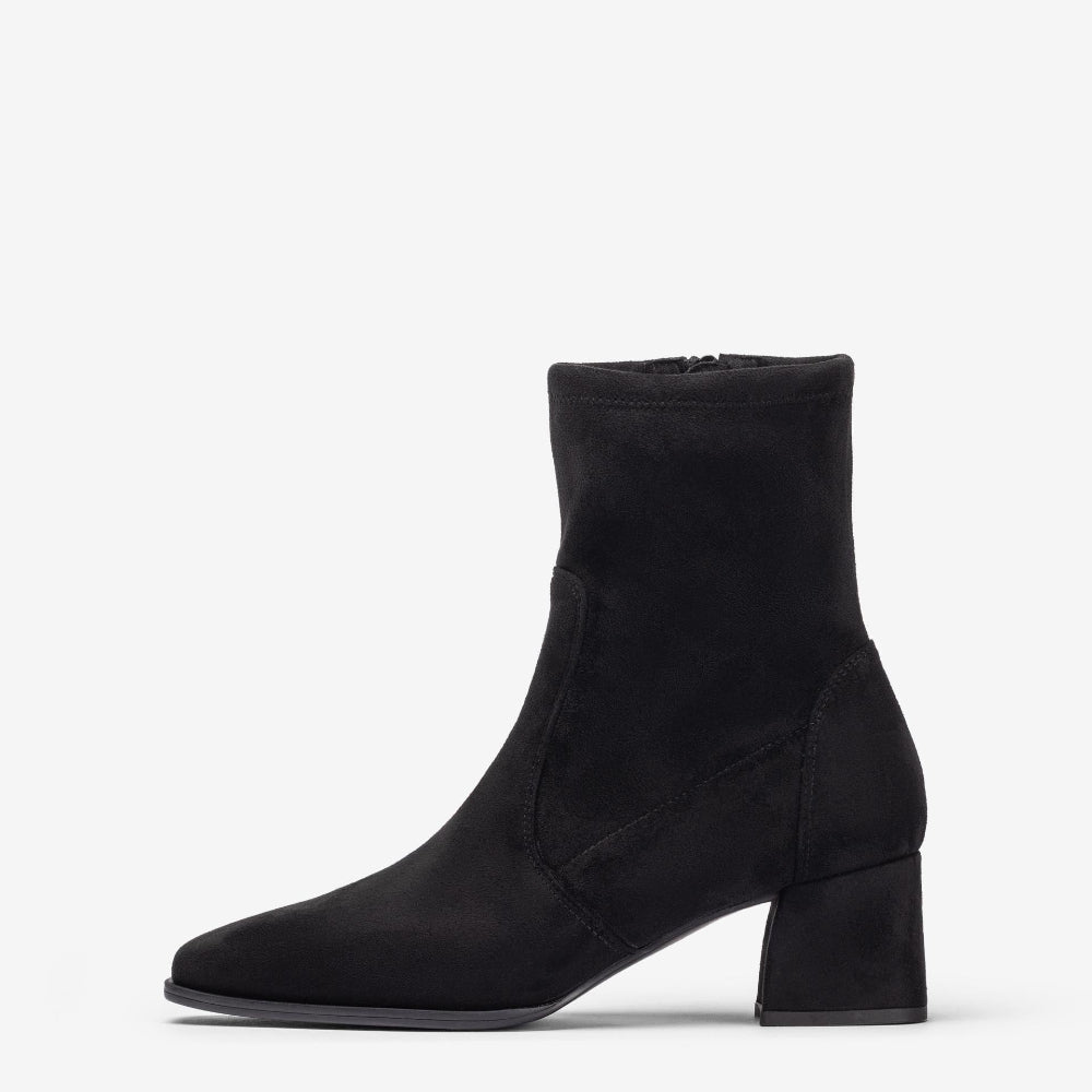 A black suede ankle boot with a block heel and pointed toe, shown in profile against a light gray background.